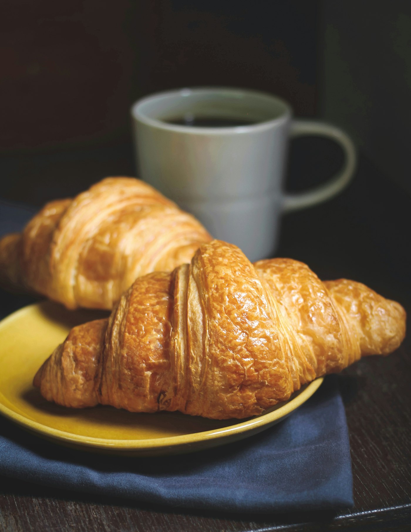 Golden croissants on a plate with a cup of coffee